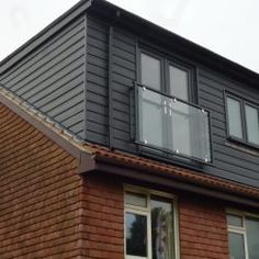 a black house with two windows and a brown roof