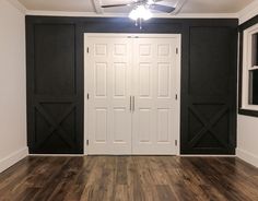 an empty room with two white doors and black shutters on the door, wood flooring