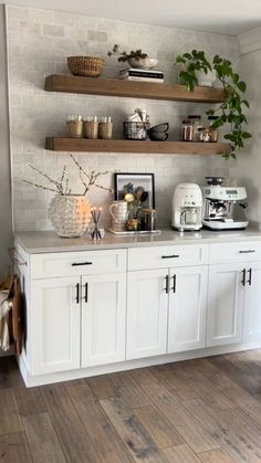 a kitchen with white cabinets and wooden shelves