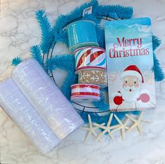 christmas wrapping supplies laid out on a marble counter top with blue tinsel and starfish