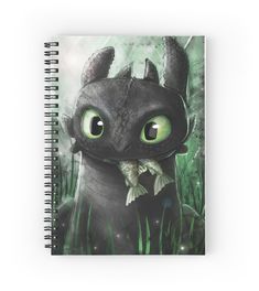 a spiral notebook with an image of a black dragon in the grass and green eyes