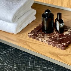 two bottles are sitting on a marble tray next to towels and soaps in front of a mirror