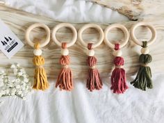 four wooden rings with tassels on them sitting on a bed next to flowers