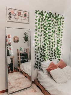 a mirror sitting next to a bed in a room with plants on the wall behind it