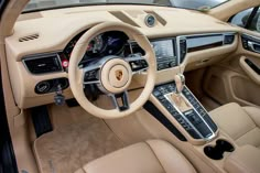 the interior of a luxury sports car with beige leather and tan stitching on the steering wheel