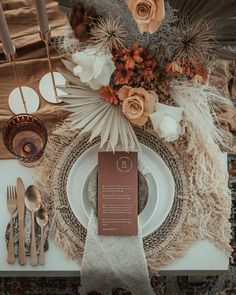 a place setting with silverware, napkins and flowers