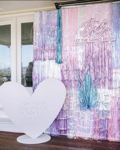 a large white heart sitting on top of a wooden floor next to a wall covered in purple and blue paint