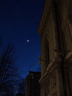 the moon is shining in the night sky over an old building with columns and windows