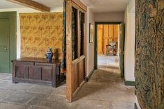 the hallway is decorated with green and yellow wallpaper, along with a wooden bench