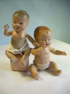 two baby dolls sitting next to each other on a table