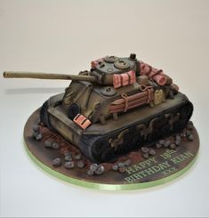 a cake shaped like a tank is sitting on a plate with the words happy birthday written on it