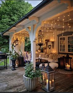 an outdoor living area with lights strung from the ceiling and potted plants on the deck