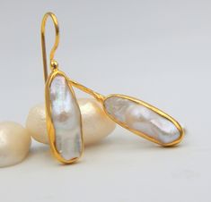 "Flat Fresh water Pearl, Drop Earrings made out of 18 karat Gold plated Sterling Silver. 100% Handmade Jewellery. PEARL: This enchanting June birthstone originates from oceans, lakes and rivers around the world. It is a timeless wardrobe staple, beloved by women of all ages. Pearls have long been associated with purity, humility and innocence. So it may be said that the June birthstone meaning is \"sweet simplicity.\" As such, pearls were traditionally given as a wedding gift. THE EARRINGS: We l Yellow Gold Teardrop Pearl Earrings With Gemstone, Gold Drop Pearl Earrings With Gemstones, Pear-shaped Gold Pearl Earrings With Gemstones, High Luster Drop Earrings For Gift, Gold Gemstone Pearl Earrings For Wedding, Gold Pearl Gemstone Earrings For Anniversary, Gift Yellow Gold Pearl Earrings With Gemstone, Yellow Gold Pearl Earrings With Gemstone For Gift, Flat Pearl Earrings