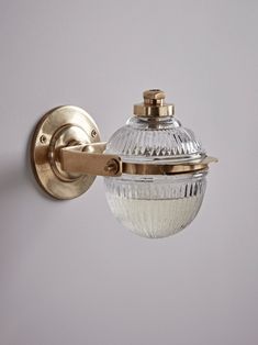 a glass light fixture mounted on the side of a wall with a metal hook and cover