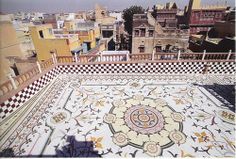 an ornate tiled floor in the middle of a city with tall buildings and rooftops