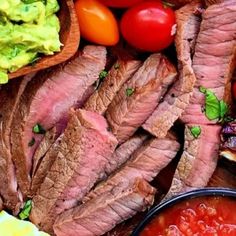 steak, tomatoes, avocado, and other foods are on the table together