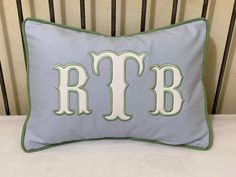 a blue and green pillow with the letter rlb on it sitting on a chair