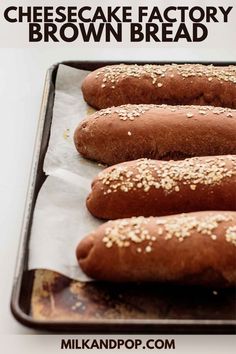 four hot dogs on a baking sheet with sesame seeds and cheesecake factory brown bread