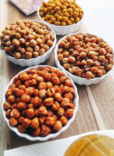 four bowls filled with nuts sitting on top of a wooden table