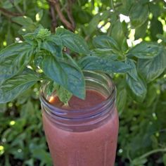 a glass filled with a pink smoothie and green leaves