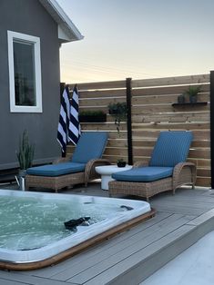 a hot tub sitting on top of a wooden deck next to two blue lounge chairs