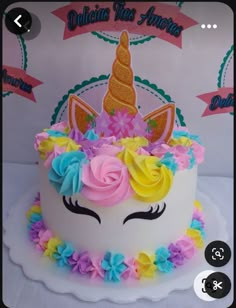 a white cake decorated with flowers and a unicorn's face on the top layer