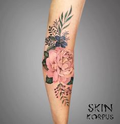 a woman's leg with flowers and leaves tattooed on her arm, in the shape of a flower