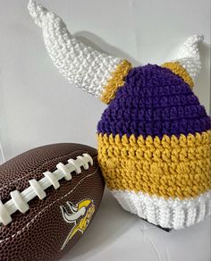 a crocheted hat and football sitting on a table next to eachother