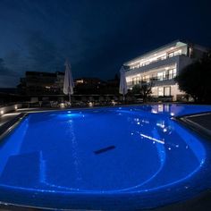 an empty swimming pool in front of a building at night