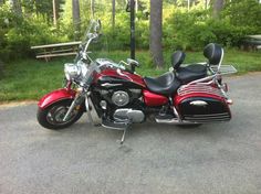 a red and black motorcycle parked on the side of the road in front of some trees