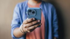 a person holding a cell phone in their right hand and taking a selfie with the camera