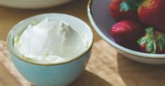 a bowl of whipped cream next to a bowl of strawberries