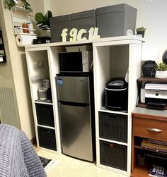 a refrigerator freezer sitting on top of a white shelf next to a desk with a computer