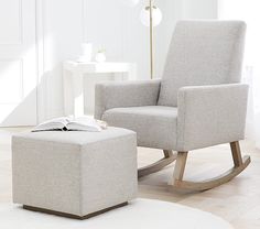 a white living room with a rocking chair and footstool next to a book