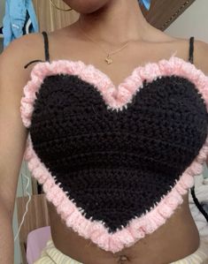 a woman wearing a crocheted heart top with pink and black ruffles