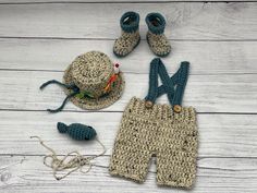 a crocheted hat, shorts and booties are laid out on a white wooden surface