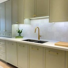 a kitchen with beige cabinets and white counter tops is pictured in this image, the sink has gold faucets on it