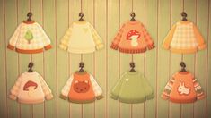 a group of baby sweaters hanging from hooks on a wooden wall next to a striped wall