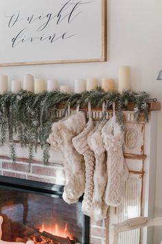 stockings hanging from a mantel over a fire place with candles and christmas decorations on it