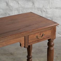 an old wooden table with two drawers on one side and a drawer on the other