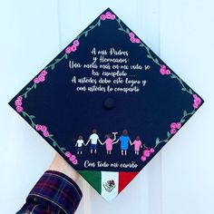 a hand holding a graduation cap decorated with children's names and flowers on it