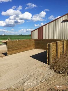 a wooden fence is in front of a building with a metal structure on the side