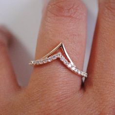 a woman's hand with a diamond ring on top of her finger and the bottom half of her wedding band