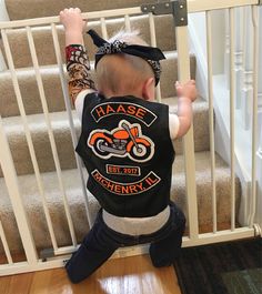 a toddler climbing up the stairs with his hands in the air and wearing a motorcycle vest