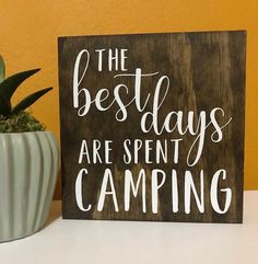 a wooden sign that says the best days are spent camping next to a potted plant