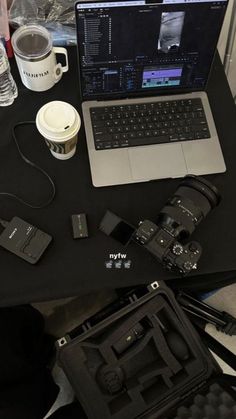 an open laptop computer sitting on top of a table next to a camera and other items