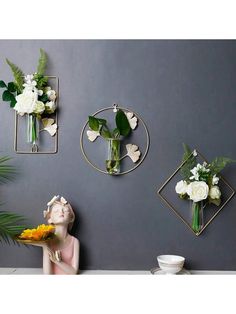 three vases with flowers are on the wall next to two mirrors and one is holding a flower