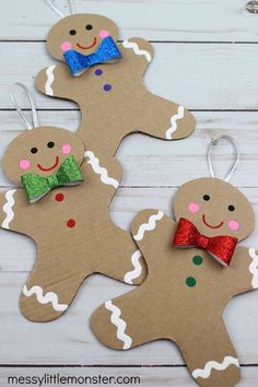 three gingerbread cutouts with bows and glitter bow ties are on a white wooden surface