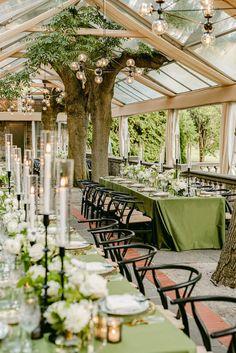 an outdoor dining area with tables covered in green tablecloths and candles on the tables