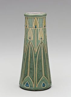 a green and gold vase sitting on top of a table